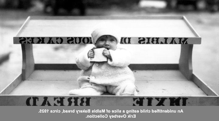 大约1925年，一个身份不明的孩子正在吃一片马尔比斯面包店的面包